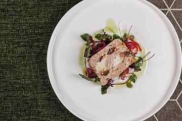 A white plate with a piece of meat and vegetables on it