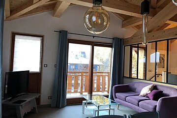 A living room with a purple couch and a glass coffee table