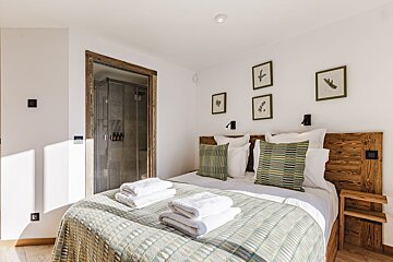 A bedroom with a large bed and a walk in shower
