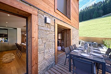A wooden house with a table and chairs outside