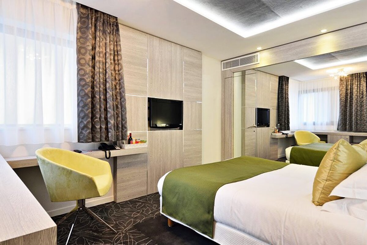 A hotel room with a bed and a yellow chair