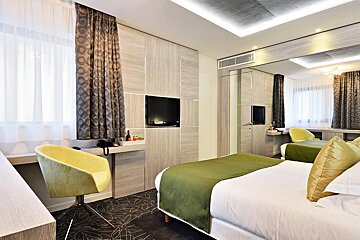 A hotel room with a bed and a yellow chair