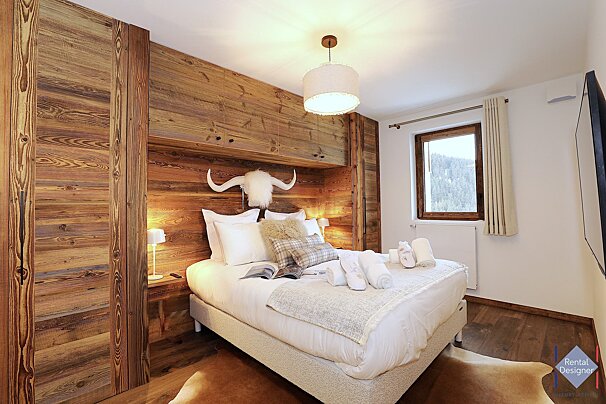 A bedroom with a bed and a rental designer logo