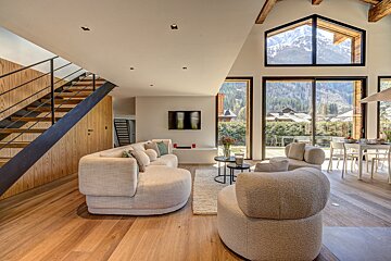 A living room with a couch and chairs and a staircase