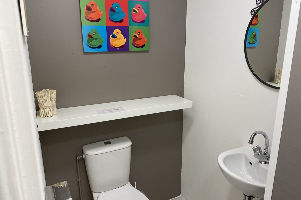 A bathroom with a picture of rubber ducks on the wall above the toilet