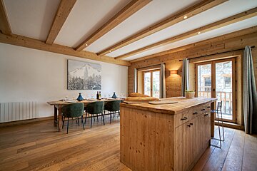 A dining room with a large wooden table and chairs