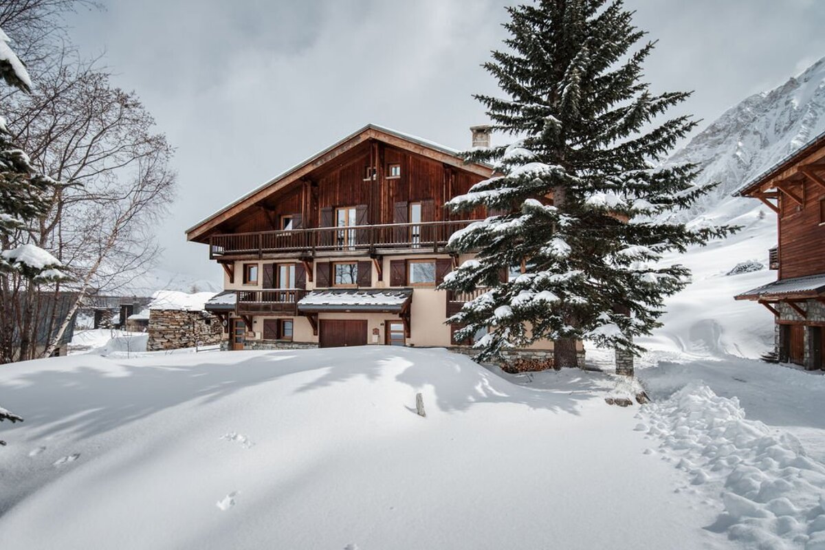 A snowy house with a tree in front of it