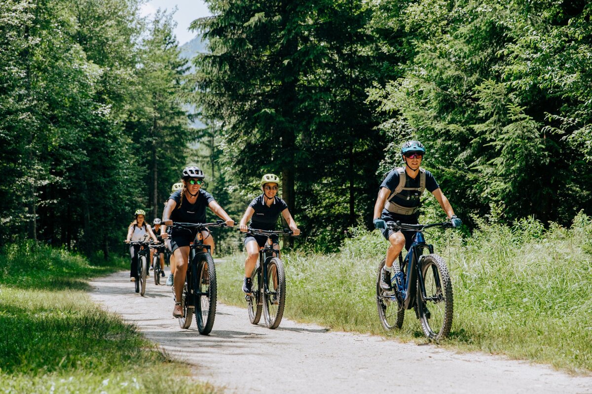 A group of people are riding bikes down a path in the woods