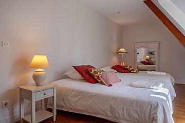 A bedroom with a bed a nightstand and a lamp