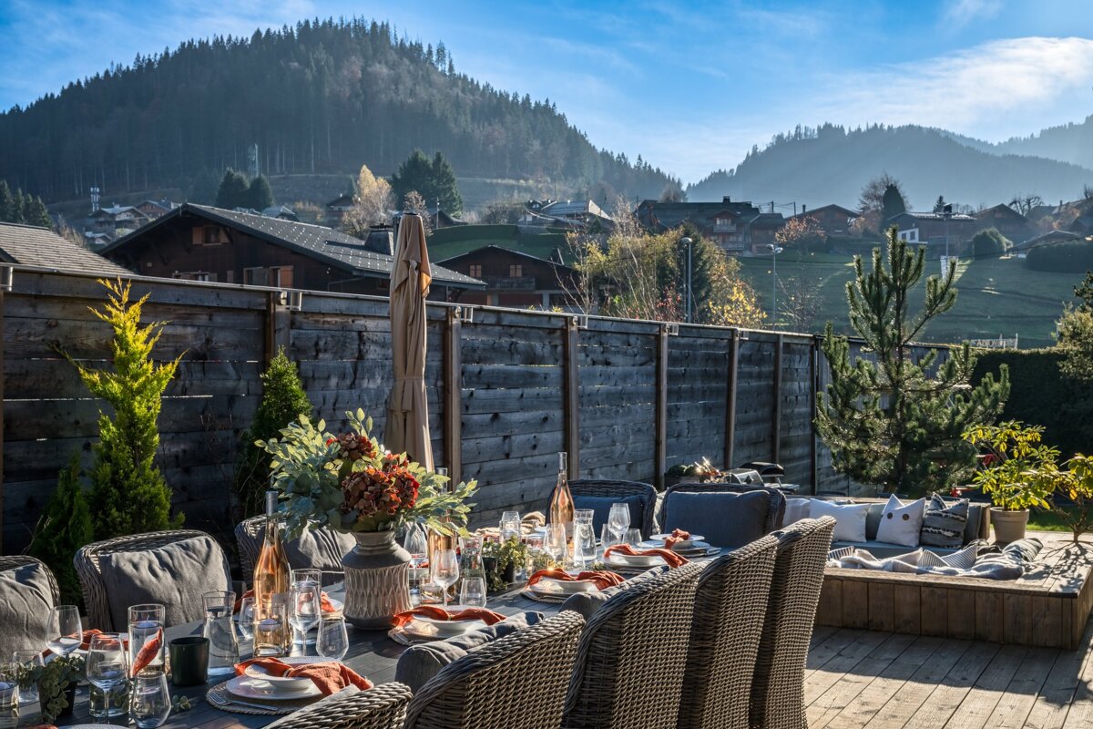 A wooden fence surrounds a dining area with mountains in the background