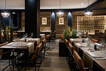 A restaurant with tables and chairs and a wall of wine bottles