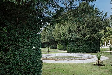 A fountain in a park surrounded by trees and bushes