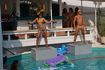 two dancers on podiums at a pool in a nightclub