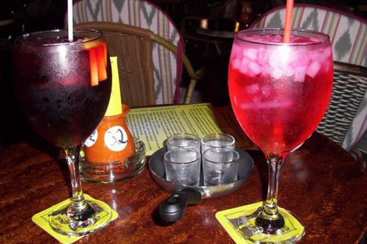 two glasses of cocktails on a dark wood table