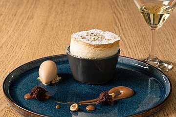 A dessert on a blue plate next to a glass of wine