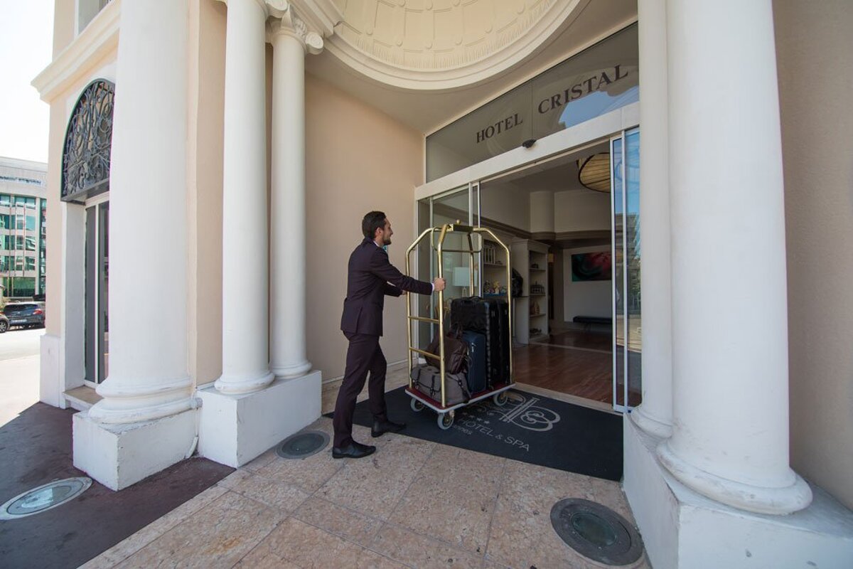A man pushes a luggage cart into the hotel cristal