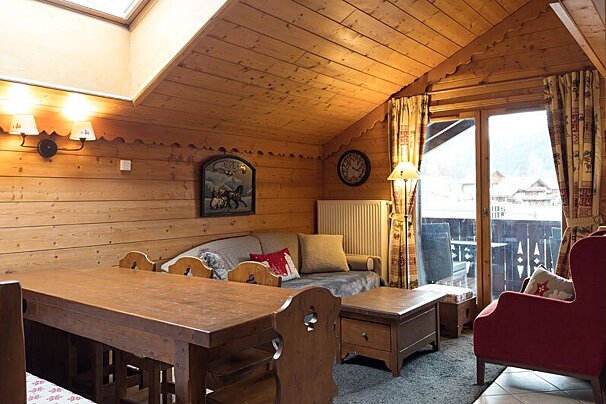 A living room with a couch a table and a clock on the wall