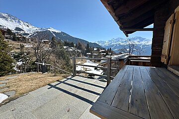 A wooden deck overlooking a snowy mountain range