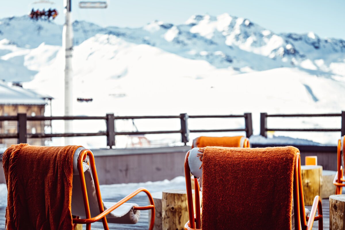 Two chairs with blankets on them in front of snowy mountains