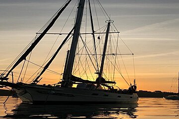 A sailboat is docked in the water at sunset
