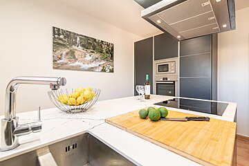 A kitchen with a bowl of lemons and avocados on a cutting board