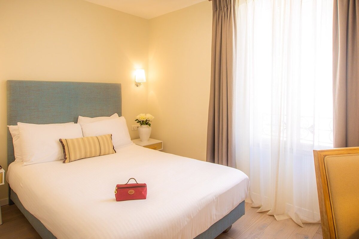 A red purse sits on a bed in a hotel room