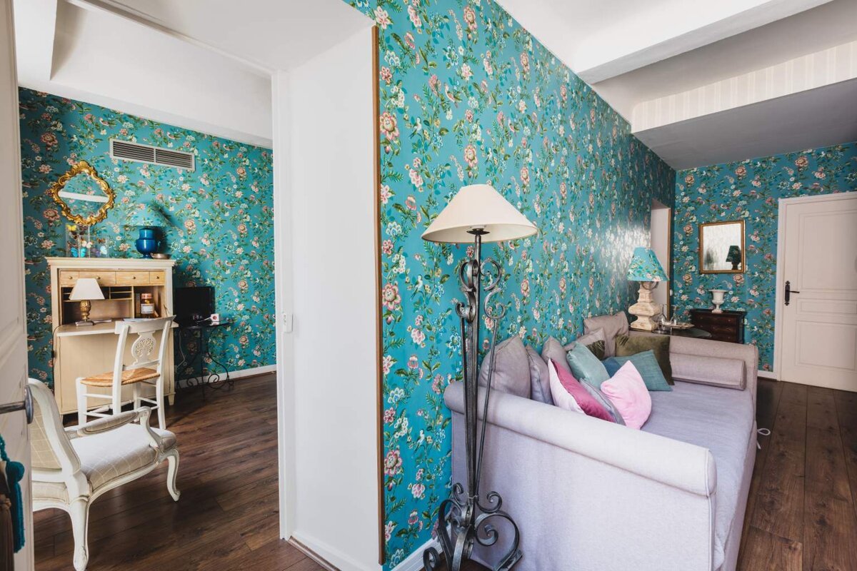 A living room with blue floral wallpaper and a couch