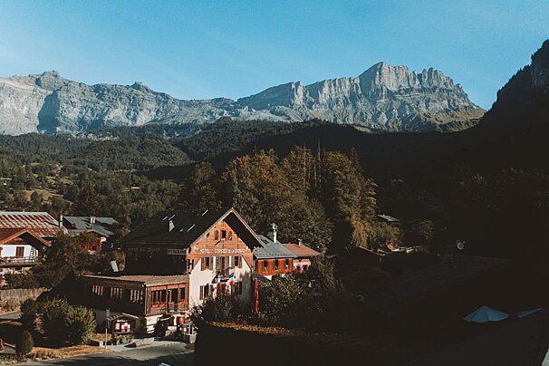A small village with mountains in the background and a building that says ' hotel de la montagne ' on it