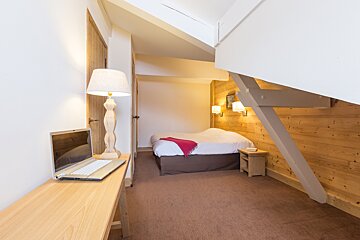 A bedroom with a bed and a laptop on a desk