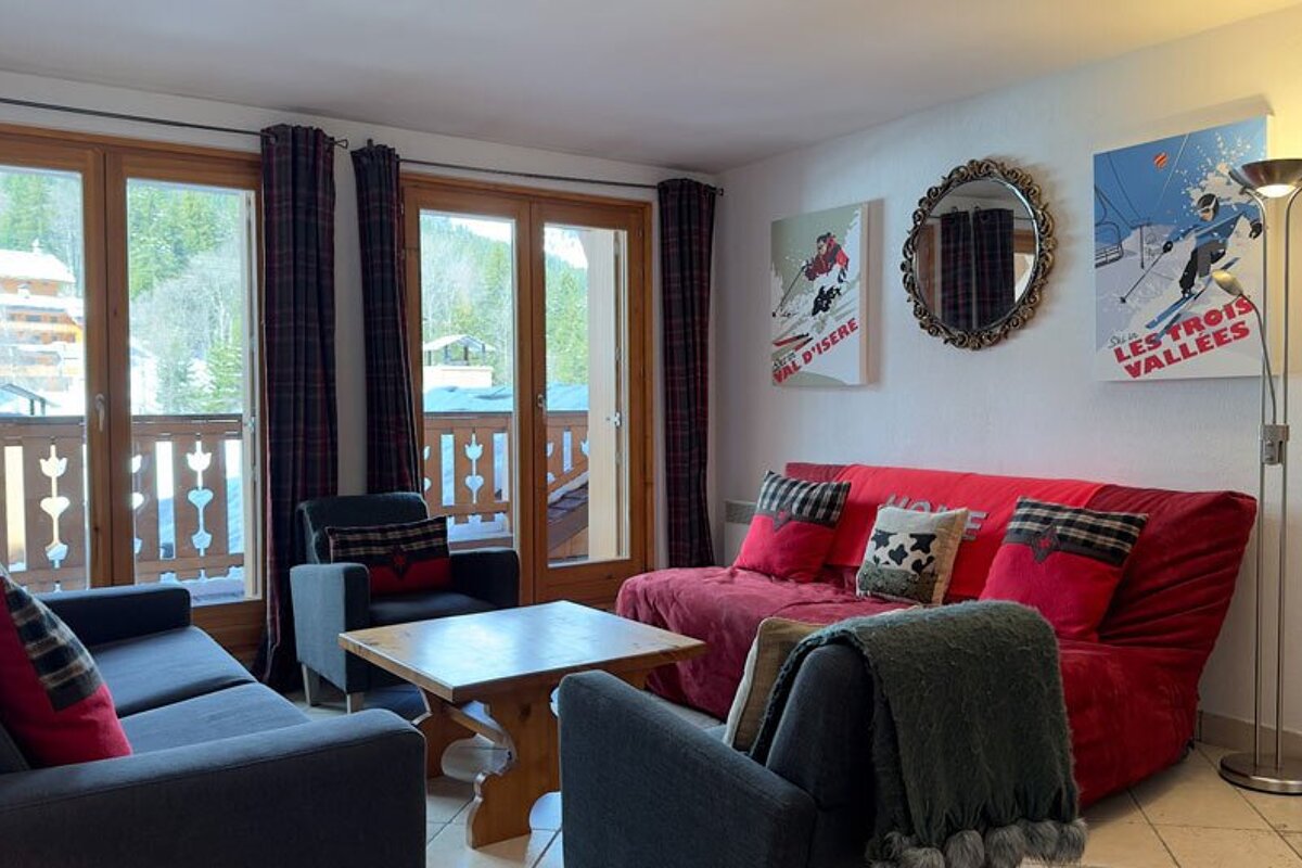 A living room with a red couch and two paintings that say les trois vallées