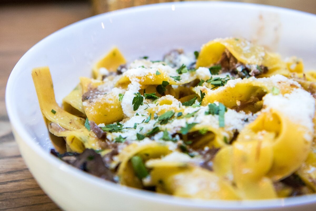 A bowl of pasta with cheese and parsley on top