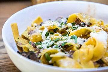 A bowl of pasta with cheese and parsley on top