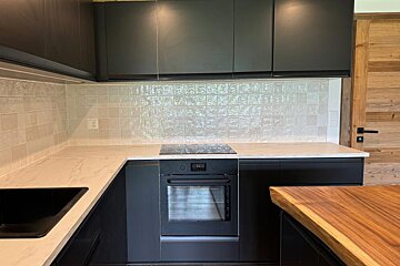 A kitchen with black cabinets and a stainless steel oven