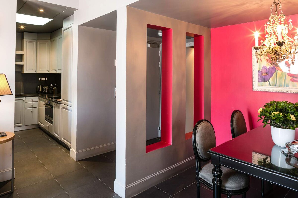 A dining room with pink walls and a chandelier
