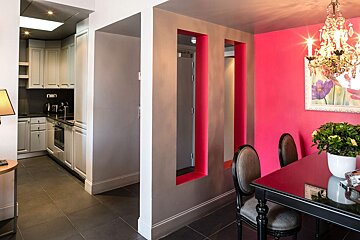 A dining room with pink walls and a chandelier