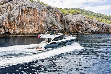 A boat is floating on the water near a rocky cliff