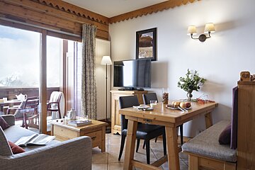 A living room with a table and chairs and a flat screen tv