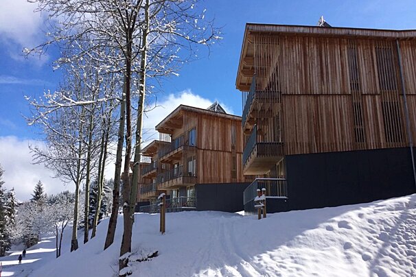 A snowy hillside with a wooden building in the background