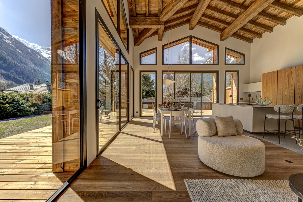 A living room with a dining table and chairs and a view of the mountains