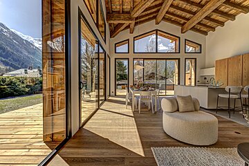 A living room with a dining table and chairs and a view of the mountains