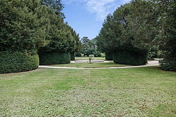 A lush green lawn with trees and bushes surrounding it