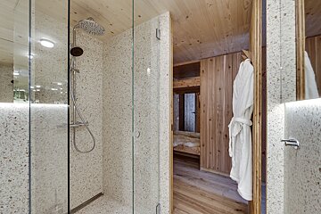 A bathroom with a shower and a robe hanging on the wall