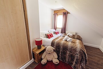 A bedroom with two beds and a teddy bear on the floor