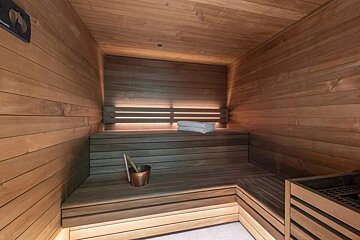 A wooden sauna with towels and a bucket of water