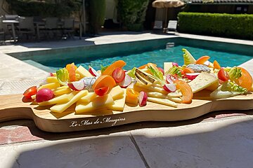 A wooden cutting board that says les mas de mougins on it