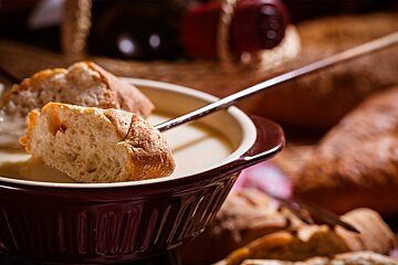 A bowl of soup with bread dipping into it