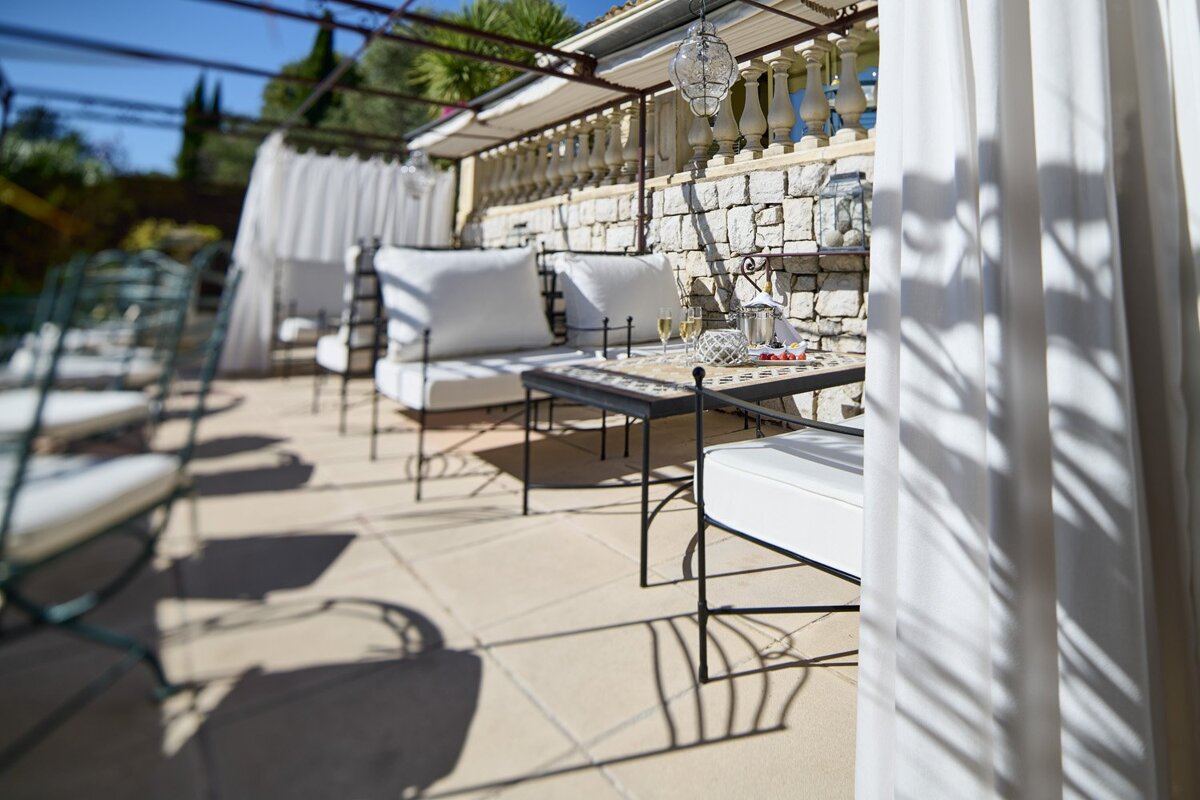 A patio with white chairs and a table with a pitcher of champagne on it