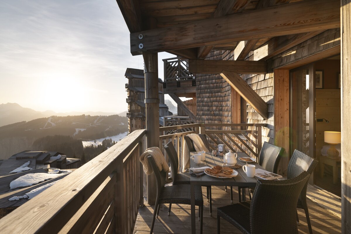 A balcony with a table and chairs and a view of the mountains