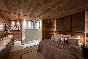 A bedroom with a large bed and a walk in shower