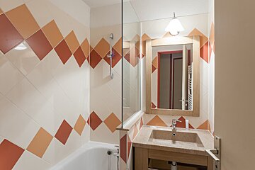 A bathroom with red and white tiles and a sink